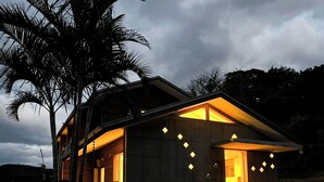 Una casa moderna con techo inclinado y ventanas amplias, rodeada de árboles.