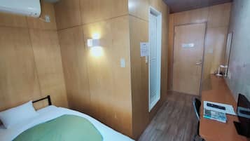 A room with a bed, a desk, a chair, and a door.