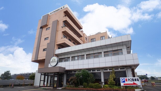 Un hotel de diseño moderno, con una entrada destacada y un letrero que indica un estacionamiento.