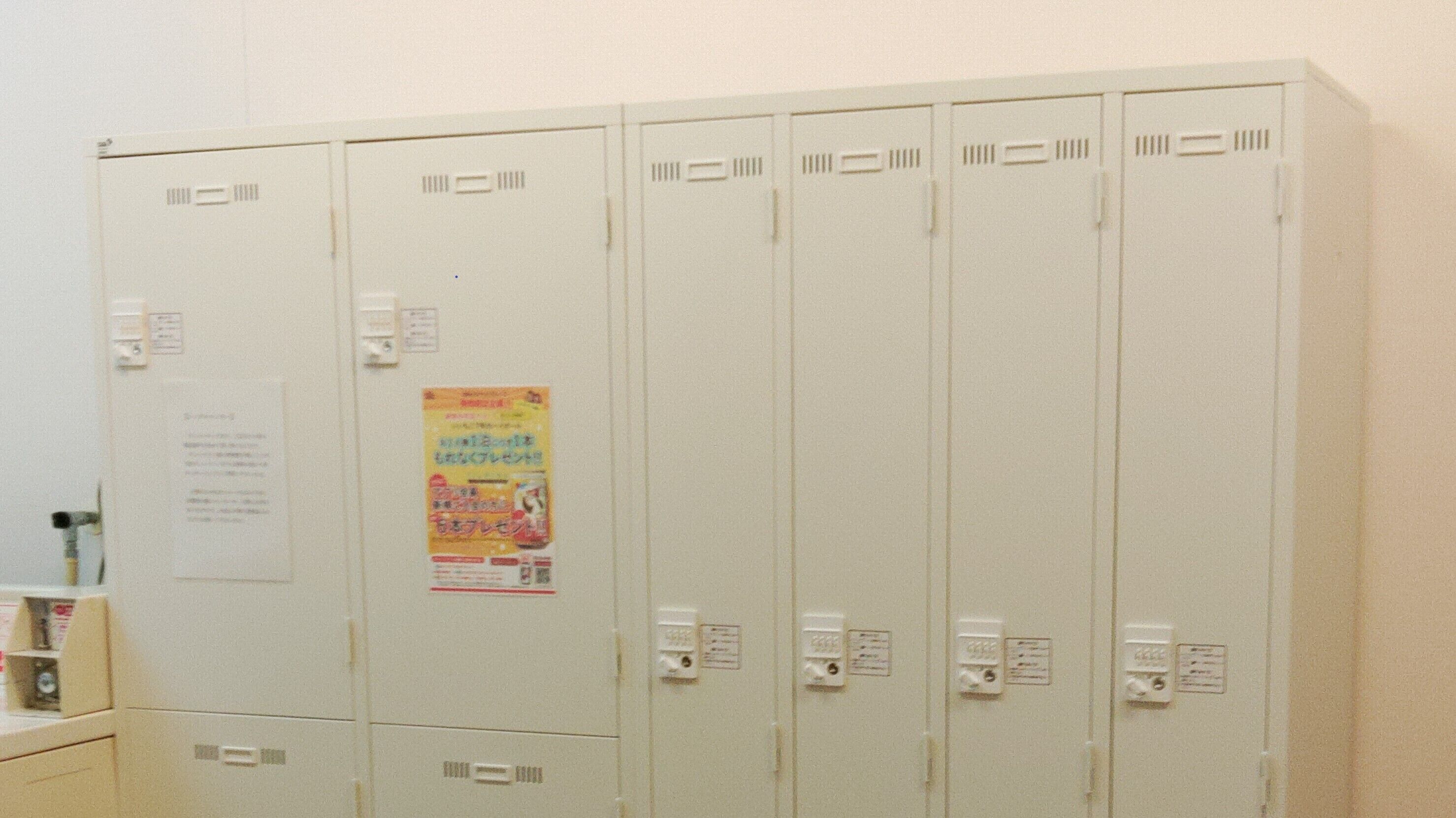 A row of white lockers with a poster and a notice on the wall.