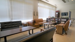 Una biblioteca moderna con asientos de cuero, mesas y una estantería repleta de libros.