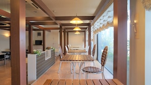 Un restaurante con mesas y sillas de madera, iluminación colgante y vistas al exterior.