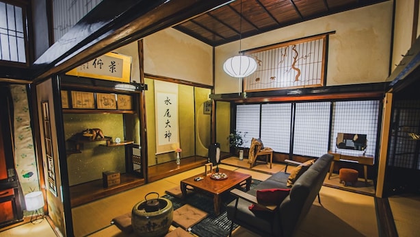 Une pièce de style japonais traditionnel, avec un sol recouvert de tatamis, une table basse, un canapé et des portes coulissantes ornées de calligraphies.