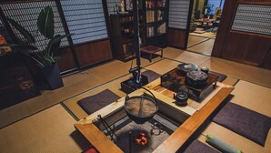 Une pièce avec un sol recouvert de tatamis, comprenant un ensemble traditionnel de cérémonie du thé japonais, une bibliothèque et une disposition décorative de tatamis.