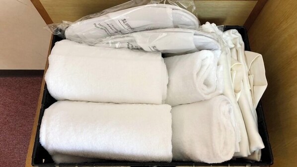 Un contenitore nero con asciugamani bianchi piegati in modo ordinato e una busta di plastica con un'etichetta.