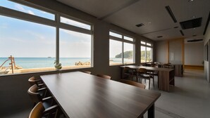 A conference room with a view of the sea, large windows, and a wooden table. - Hashimotoya (Himi)