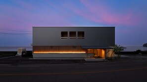 A modern two-story building with a flat roof, a large window on the upper floor, and a sloped roof with a small porch area. - Hashimotoya (Himi)