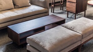 Uma sala de estar moderna com um sofá, uma mesa de centro de madeira e um banquinho.