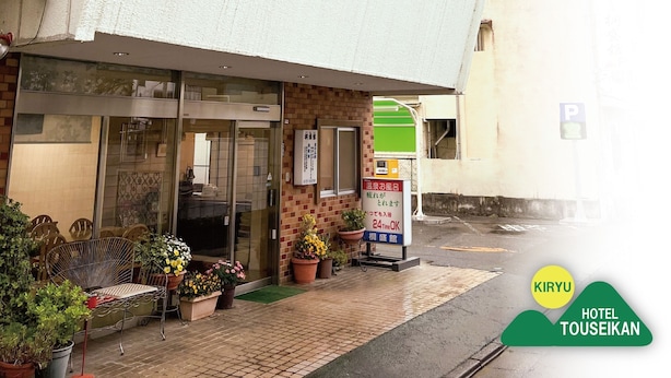 A hotel entrance with a glass door, a signboard, and potted plants outside. - Kiryu Hotel Toseikan (Kiryu)