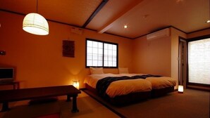 A traditional Japanese-style bedroom with tatami flooring, a low bed, a futon, a wooden bench, and a shoji screen window. - Tsukiyado Rakku (Ito)