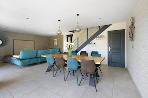 Een eetgedeelte met een houten tafel en stoelen, een bank en een trap.