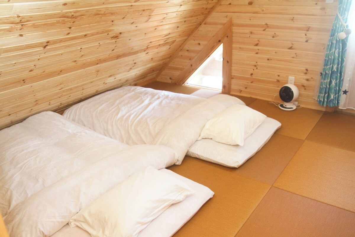 A room with two beds, a fan, and a window.