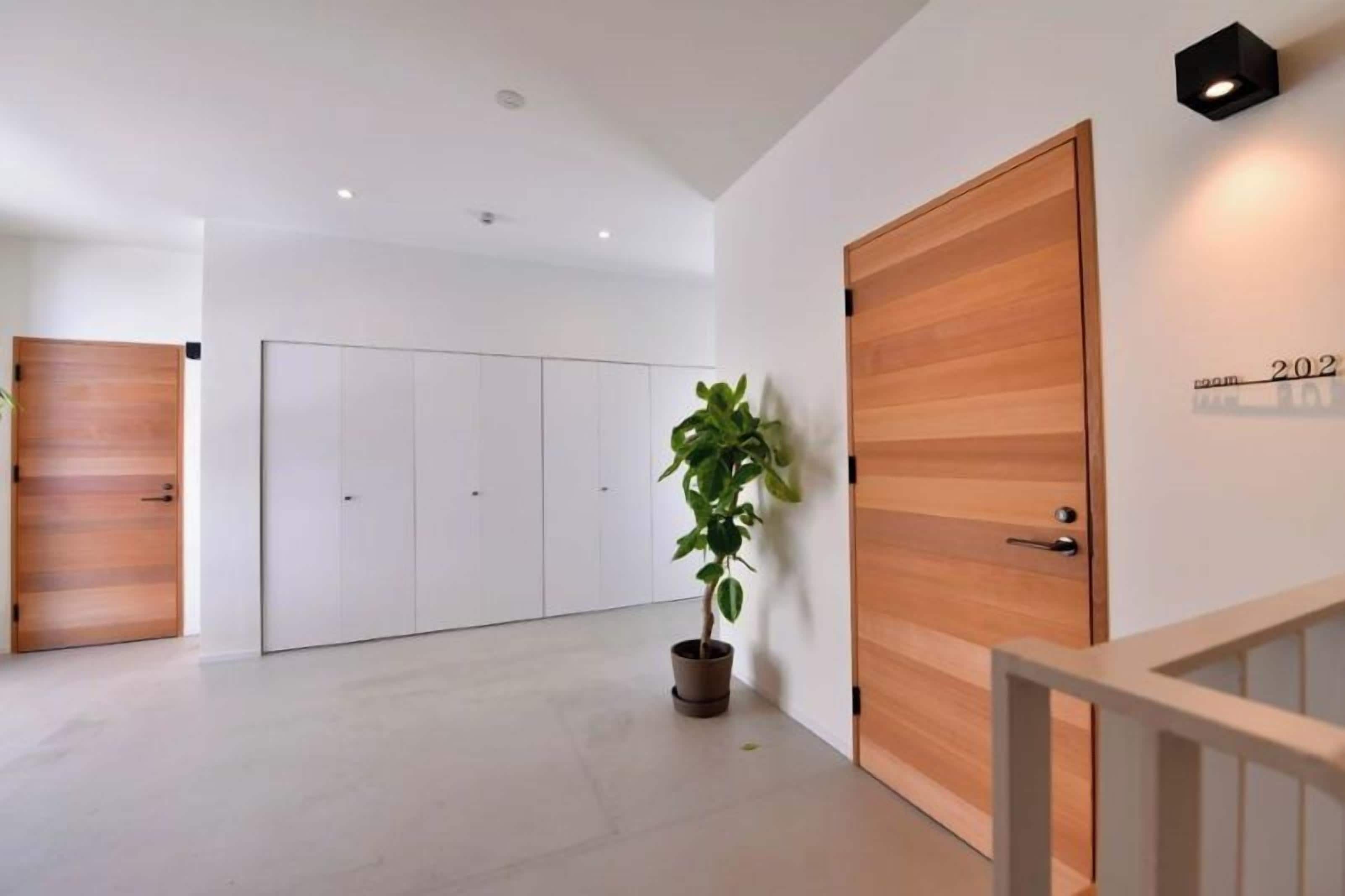 Un pasillo de hotel con una puerta de madera, una planta en maceta y un letrero que indica la habitación número 202.