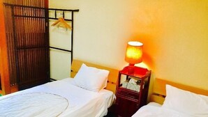 A room with two single beds, a bedside table with a lamp, and a wooden wardrobe. - Hotel Saboten Apartment (Miyoshi)