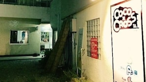 A building with a sign reading "Coco's Cross" and a parking sign. There is a staircase leading to an upper level. - Hotel Saboten Apartment (Miyoshi)