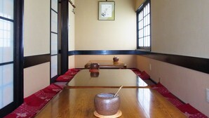 A traditional tatami room with a low table, a stone cup, and a small bowl. - Town Hotel Ishii (Maniwa)