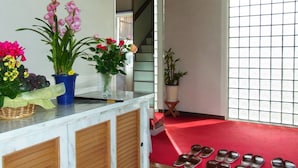 A room with a reception desk, potted plants, a staircase, and a red carpet. - Town Hotel Ishii (Maniwa)