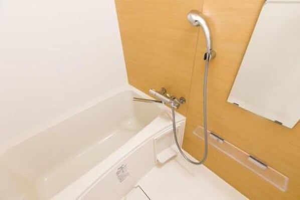 A bathroom with a white bathtub, a shower, and a wooden panel wall. - Mr.kinjo in Shanti Van Tsubogawa Station (Naha)