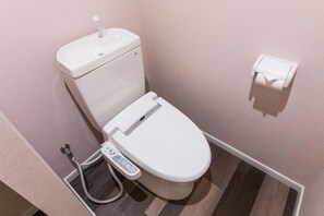 A modern toilet with a control panel, a toilet paper holder, and a bidet attachment. - Mr.kinjo in Shanti Van Tsubogawa Station (Naha)