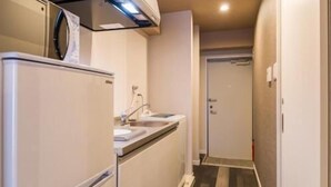 Un couloir étroit avec un coin cuisine comprenant un réfrigérateur, un évier et une cuisinière.