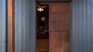 A wooden door leading into a room with a ceiling fan and a red cabinet. - Tomareru Himitsukichi L-base (Matsumoto)