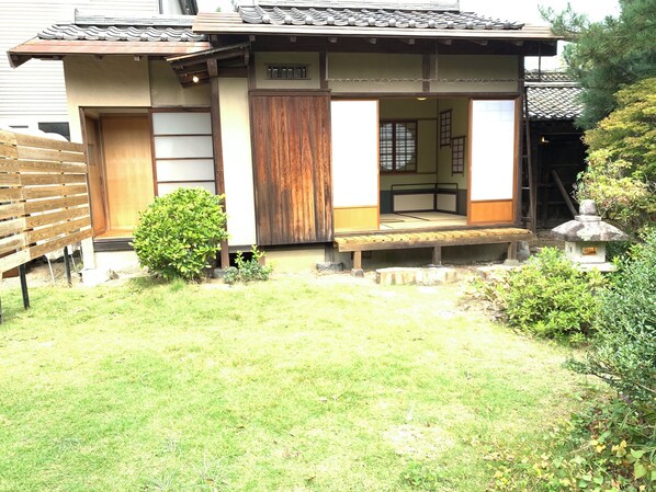 A traditional Japanese house with a wooden exterior, a small garden, and a stone lantern.