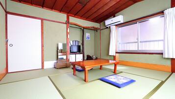 Perinteinen japanilainen huone, jossa on tatamimatto, matala puupöytä, televisio ja ilmastointilaite.