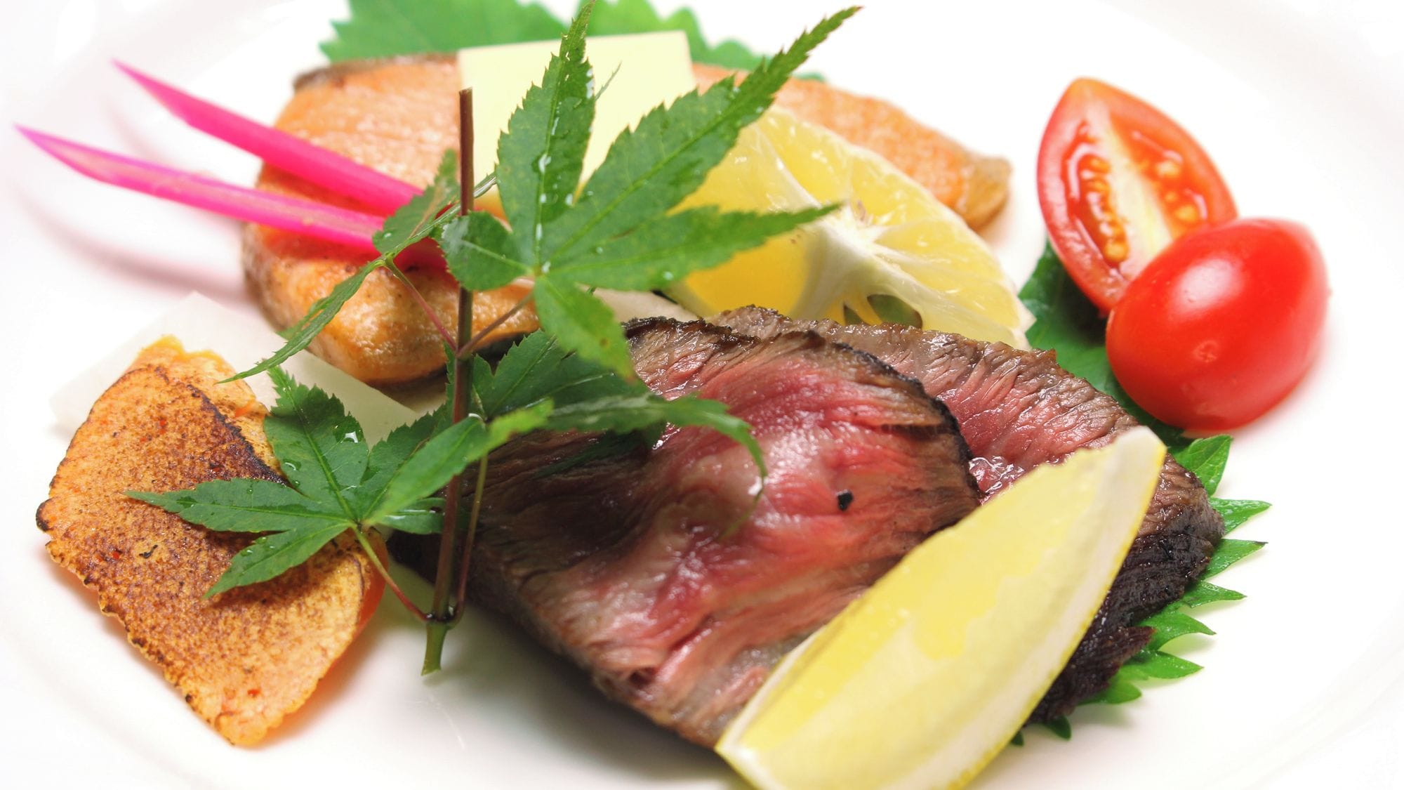 A plate with a grilled steak, lemon wedges, cherry tomatoes, and a garnish of green leaves.
