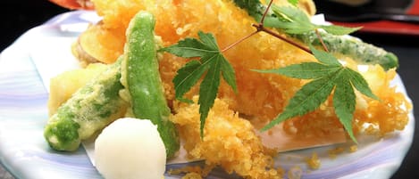 A plate with tempura vegetables and a white dumpling.