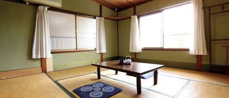A traditional Japanese room with tatami flooring, a low table, and sliding doors.