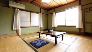 A traditional Japanese room with tatami flooring, a low table, and sliding doors. - Ryori Ryokan Marumo (Takashima)