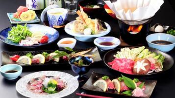 Variedad de platos japoneses, como sashimi, tempura y una preparación para hot pot.