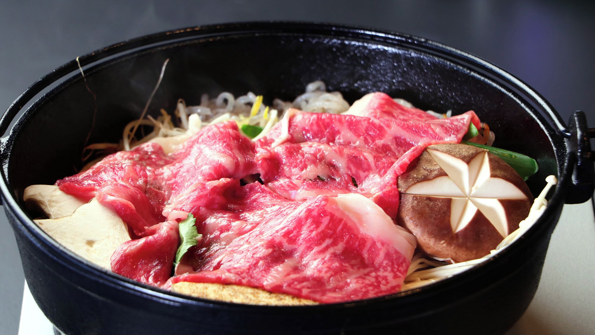 A bowl of food with various ingredients including meat, vegetables, and a decorative element.