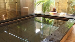 A glass-bottomed pool with a drain, surrounded by bamboo walls and potted plants. - Ryori Ryokan Marumo (Takashima)