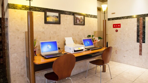 A reception desk with two laptops, a printer, and two chairs in a lobby with marble walls and framed pictures. - Hotel New Global (Isahaya)