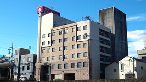 A multi-story hotel with a prominent red sign on the corner, a flat roof, and a modern architectural style. - Hotel New Global (Isahaya)