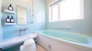 A bathroom with a bathtub, a toilet, a sink, and a window. - Fuji Viewest Villa Rakuwa (Fujikawaguchiko)