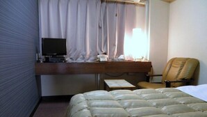 A hotel room with a bed, a desk with a computer, a chair, and a window with curtains. - Business Hotel Tenmonkan (Kagoshima)
