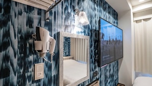 A hotel room with a large mirror, a mounted television, and a hairdryer on the wall. - Hotel Prism (Nagoya)