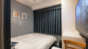 A hotel room with a bed, a desk, a chair, a TV, and a window with curtains. - Hotel Prism (Nagoya)
