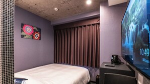 A hotel room with a bed, a TV displaying a waterfall, a clock showing 10:49, and a decorative wall piece. - Hotel Prism (Nagoya)
