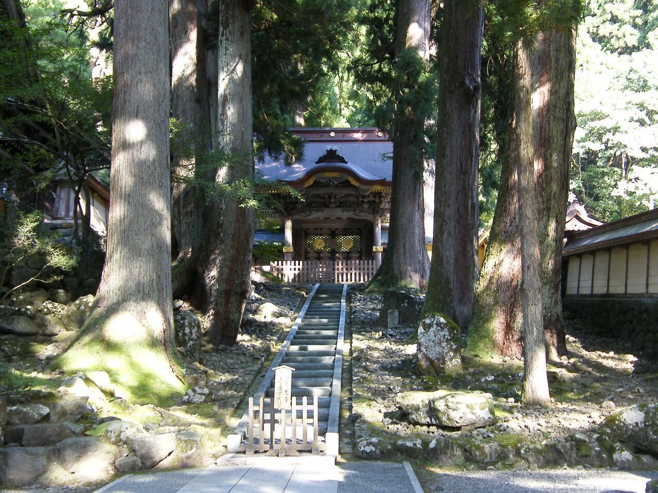 Um jardim japonês tradicional com um caminho de pedra que leva a uma estrutura de madeira.