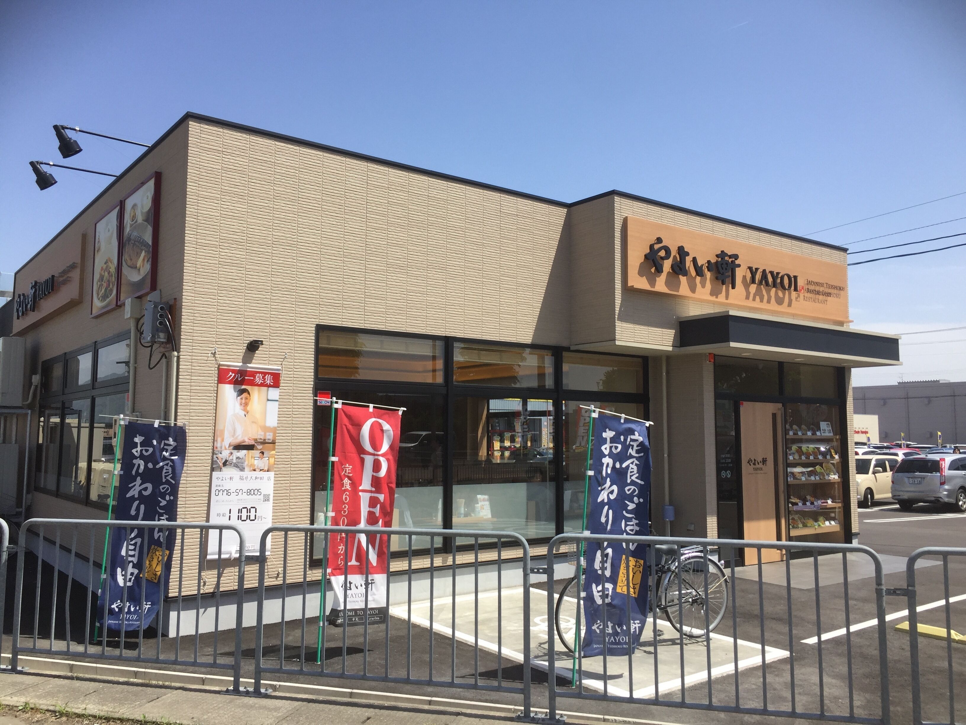 A restaurant with a sign reading "YAYOI JAPANESE RESTAURANT". There are banners on the fence advertising the restaurant.