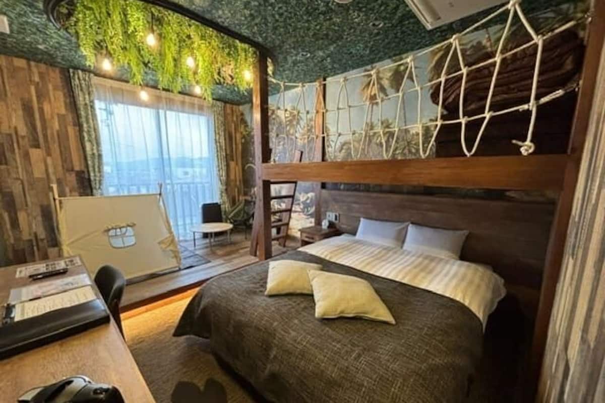 Un dormitorio acogedor con una litera, un escritorio con hervidor y una ventana con cortinas.