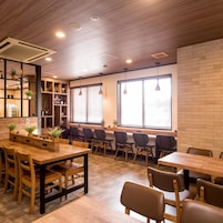 A modern interior with wooden tables and chairs, a brick wall, and a ceiling with recessed lighting.