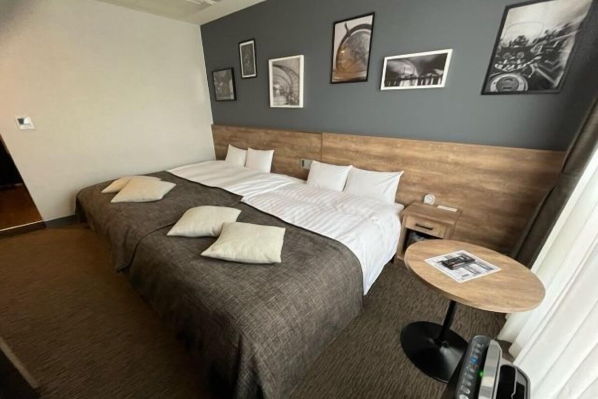 A hotel room with a large bed, a bedside table with a lamp, and a small round table with a magazine.