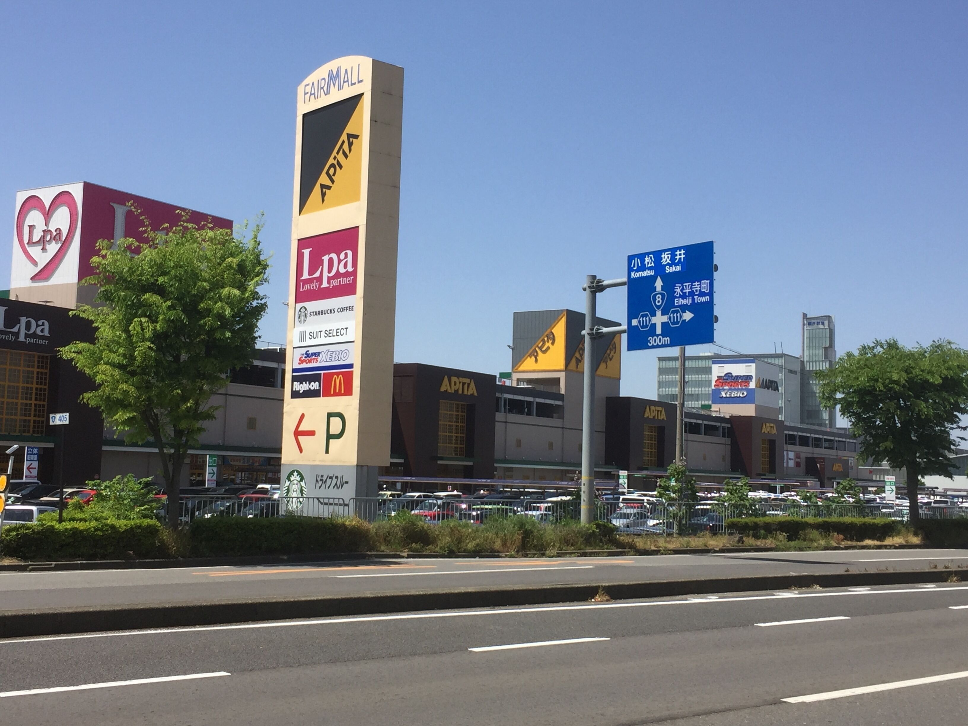 Un'area commerciale con un cartello evidente per Lpa, un segnale di parcheggio e indicazioni per attrazioni locali.