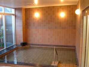 Um espaço de spa com paredes revestidas de azulejos e uma piscina retangular.