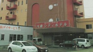 Un hotel de varios pisos con fachada roja y color beige, múltiples balcones y un letrero que indica que es un hotel.