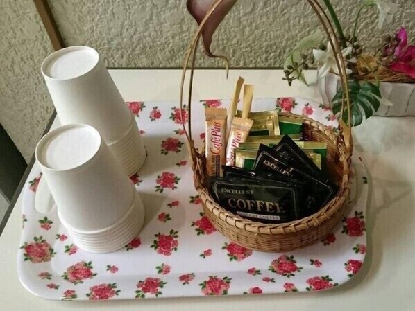 Un plateau avec un panier de café et une nappe à motifs floraux.